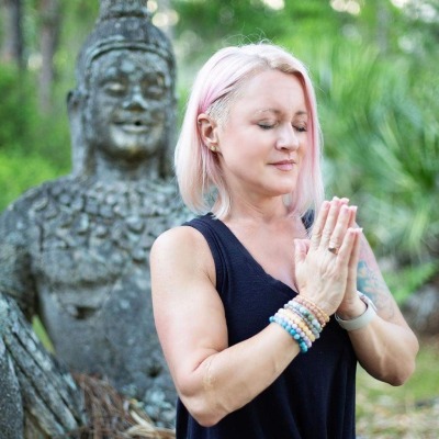 Sarah Deeley Porter in a yoga pose in front of a buddha statue